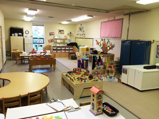 Older preschool classroom with a variety of centers and activities including a train table, an art center and a dollhouse.
