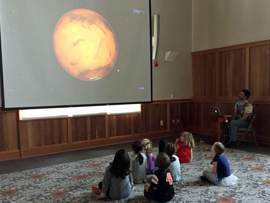 Pre-Kindergarten children looking at a picture of the moon on a big screen