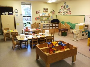 View of preschool room with sand table, art center and dramatic play area with no children